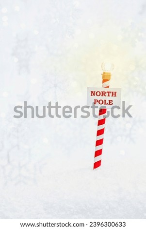 The North Pole on candy striped pole with glowing light in the snow