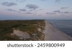 North Sea coastline in west Jutland, Denmark, at sunset, sand dunes covered in green vegetation.