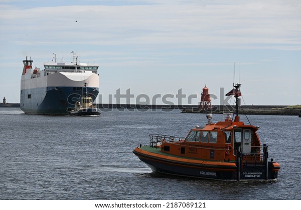North Shields, England - August 6 2022:\
Nordic Ace car transport vessel entering mouth of River Tyne\
supported by RNLI lifeboat and pilot tug\
vessels