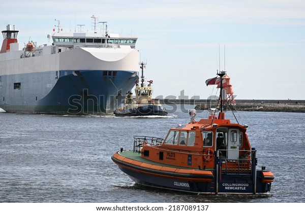North Shields, England - August 6 2022:\
Nordic Ace car transport vessel entering mouth of River Tyne\
supported by RNLI lifeboat and pilot tug\
vessels