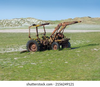 North Uist, Outer hebrides, Scotland, United Kingdom 05.15.2022. JCB in derelict condition left in a field to rust away with sand dunes and blue sky to background. Agricultural Machine rusting away