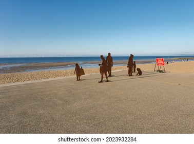 North Wales Stock Photo: Colwyn Bay Promenade, Beach,  Wales, UK,  July 13, 2021, Metal Statues Of Men, Women And Children And A Covid Warning Sign With Text Space. 