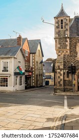 North Wales: Vertical Stock Photo Of Welsh Flag Flying On Berry Street, With Corner View Of Old Library And Narrow Road Leading To The Harbour. 9th June 2020. 