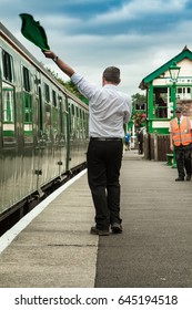 NORTH WEALD, UK - 20 JULY 2013:  Man Signals With A Flag For Train To Depart On Epping Ongar Railway