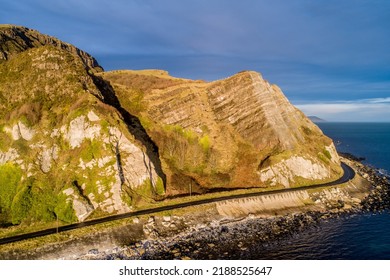 Northern Ireland, UK. Atlantic coast. Cliffs and Antrim Coast Road, a.k.a. Causeway Costal Route. One of the most scenic coastal roads in Europe. Aerial view near Garron Point in sunrise light