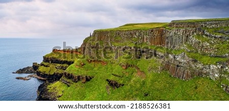 Northern Ireland, UK. Cliffs at Atlantic coast in County Antrim with visible geological strata and volcanic basalt formation of natural hexagonal poles resembling organ pipes. Aerial panorama