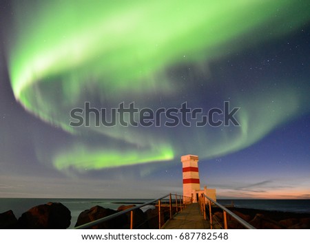 Northern light is above an old lighthouse of Gardur in southwestern Iceland which stands alone at seaside of the North Atlantic Ocean.