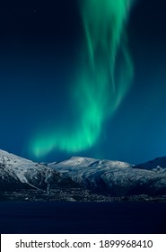 Northern lights above snow covered mountains and the Town of Narvik in Norway