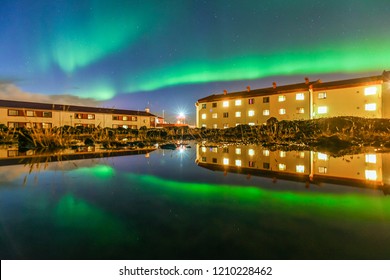 Northern Lights (Aurora) With Buildings Reflection In The Water Near Keflavik Airport , Iceland