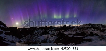 Northern Lights bursting above an Arctic rocky landscape