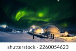 Northern Lights also known as aurora, borealis or polar lights at cold night over igloo village. Beautiful night photo of magic nature of winter landscape with grain.