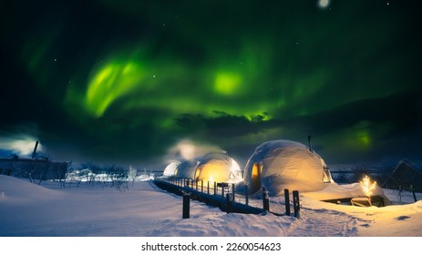 Northern Lights also known as aurora, borealis or polar lights at cold night over igloo village. Beautiful night photo of magic nature of winter landscape with grain.