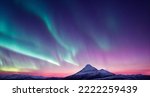 Northern Lights over snowy mountains. Aurora borealis with starry in the night sky. Fantastic Winter Epic Magical Landscape of snowy Mountains.  