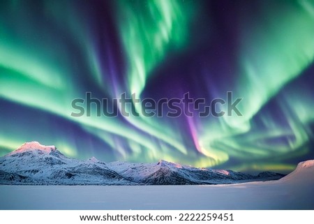 Northern Lights over snowy mountains. Aurora borealis with starry in the night sky. Fantastic Winter Epic Magical Landscape of snowy Mountains.  