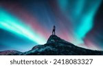 Northern lights and sporty woman on mountain peak at night. Aurora borealis and silhouette of a girl on top of rock. Landscape with polar lights. Starry sky with bright aurora. Travel background