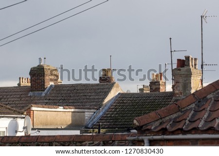 Northern town tiled roof tops with chimneys and aerials UK. Cramped urban working class housing. Old town building rooves.