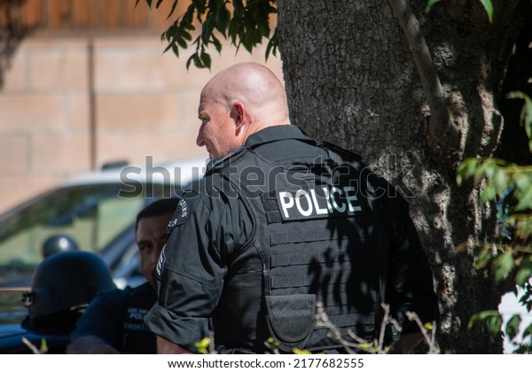 Northridge, California, United States -  June\
29, 2022: A LAPD sergeant stages on a community street prior to a\
drug policy enforcement raid with a multi-agency task force, with a\
vest saying\
\