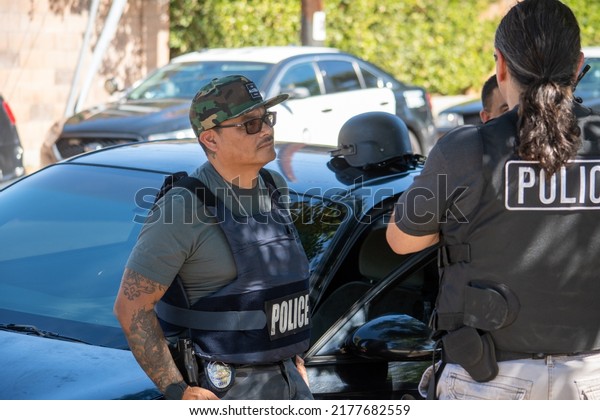 Northridge, California, United States -  June 29,\
2022: A multi-agency task force including LAPD Narcotics detectives\
stages on a community street prior to a drug  enforcement raid\
wearing vests.