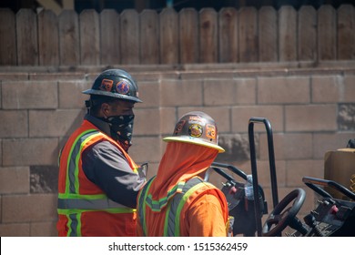 Northridge, California / USA -  September 25, 2019: L.A. Road Construction Crew Wearing Hardhats Operating Road-resurfacing Machinery To Apply More Asphalt