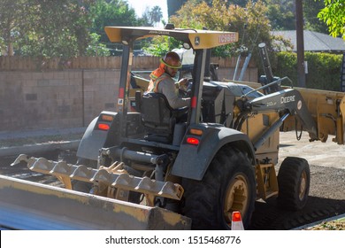 Northridge, California / USA -  September 25, 2019: 210L EP John Deere Tractor With Operator In Hard Hat Working At A Repaving Project In Northridge.