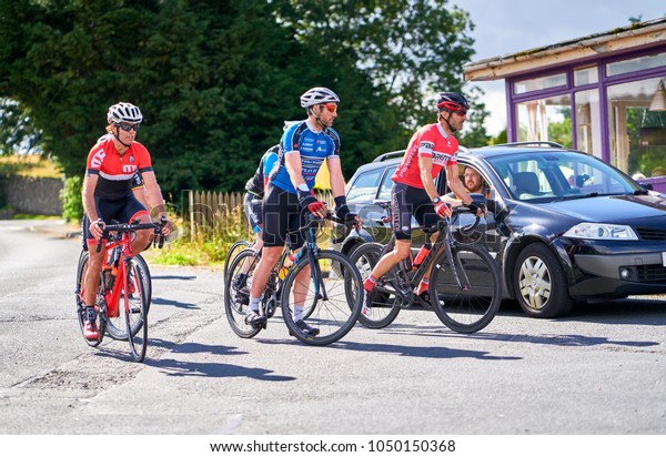 NORTHUMBERLAND, ENGLAND, UK - AUGUST 26, 2016: A\
group of cyclists and their support car on a bike race on country\
roads on a sunny day in the\
UK.
