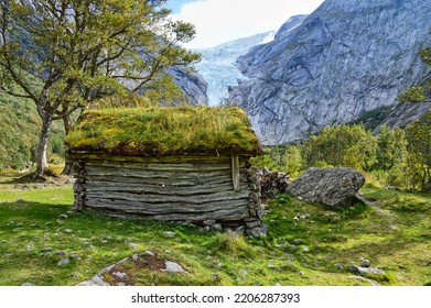 Norway Briksdal wooden hut with grass roof in a meadow near waterfall and glacier in norway in september