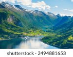 Norway. Cruise ship in the Norwegian fjord. High mountains and reflections on the surface of the water. Clouds over the rocks. Vacation and travel in summer Norway.