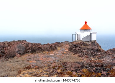 The Norway Sea Beacon With A Red Top And A Stone Footpath On The Edge Of The Rock Over The Foggy Sea