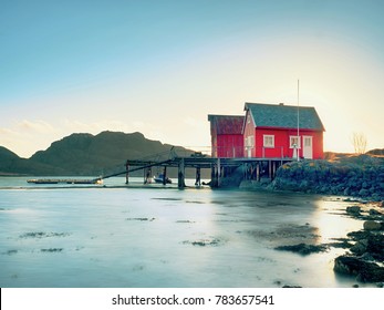 Norwegian coast landscape with a typical red house.  Wooden red house on the seaside, first warm spring day. - Powered by Shutterstock