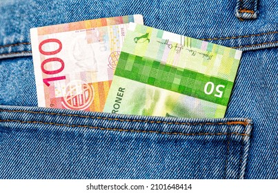 Norwegian krone banknotes sticking out of the blue jeans pocket