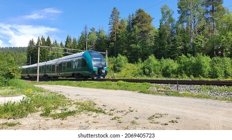 Norwegian Vy passenger train passing on a forest rail road track outside of Oslo, Norway - July 15, 2021