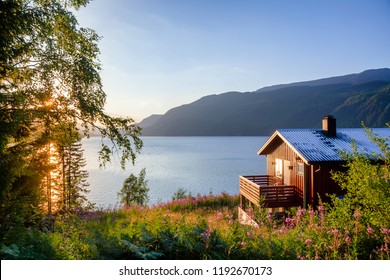 Norwegian wooden summer house (Hytte) with terrace overlooking scenic lake at sunset, Telemark, Norway, Scandinavia