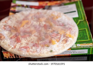 Norwich, Norfolk, UK - April 30 2021. Close and selective focus of a Tesco branded ready made frozen stone baked thin sweet chili chicken pizza in its packaging 
