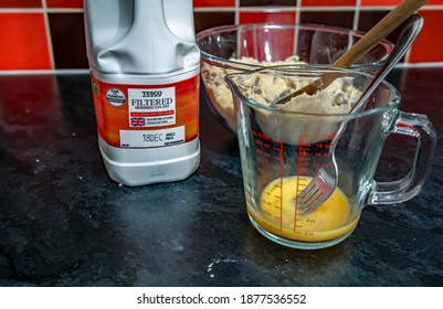 Norwich, Norfolk, UK – December 06 2020. Illustrative editorial photography of a of bottle of Tesco filtered skimmed milk together with a cracked egg in a pyrex jug 