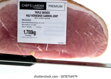 Norwich, Norfolk, UK – December 19 2020. An illustrative editorial photo of a close up of a Chefs Larder branded triple smoked gammon joint and a sharp knife on a plain white background