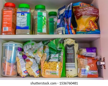 Norwich, Norfolk, UK – October 20 2019. Selective focus on the bag of pasta on the bottom shelf of a kitchen cupboard full of staple ingredients