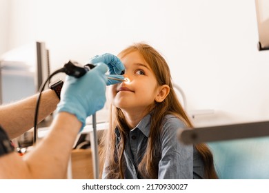 Nose Endoscopy Of Child. Rhinoscopy Procedure With Rhinoscope. ENT Doctor Otolaryngologist With Headlight Treat Nose Kid Patient