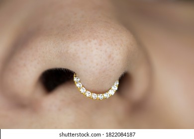 Nose piercing septum. Beautiful piercing jewelry. Macro shot. Selective focus.