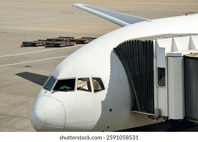 Nose of an unmarked large long-haul jet attached to a passenger boarding bridge at an airport terminal. No people.