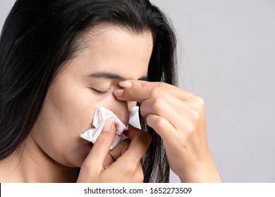 Nosebleed , a young woman suffering from nose bleeding and using tissue paper for stop bleeding. Healthcare and medical concept.