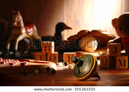 Nostalgic antique wooden spinning top play time toy and traditional collection of old wood children toys with baseball glove and teddy bear with vintage alphabet blocks and marbles in an attic