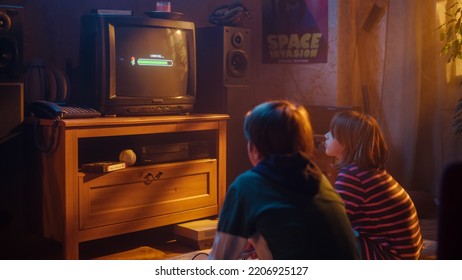 Nostalgic Childhood Concept: Young Boy and Girl Playing Old-School Arcade Video Game on a Retro TV Set at Home in a Room with Period-Correct Interior. Kids Waiting For Level to Load.