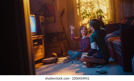 Nostalgic Childhood Concept: Young Brother And Sister Playing 8 Bit 2D Arcade Video Game On A Retro TV Set At Home In A Room With Period-Correct Interior. Friends Win The Level And High Five.