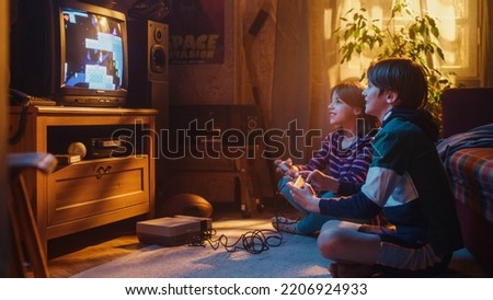 Nostalgic Childhood Concept. Young Brother and Sister Playing Old-School Arcade Video Game on Retro TV Set in a Living Room with Period-Correct Interior. Friends Spend the Day at Home Playing Games.