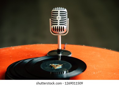 nostalgic image of a 50's microphone standing on an old orange table with old vinyl records - Powered by Shutterstock