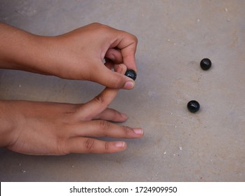 Nostalgic Indian Games - A Child Playing With Glass Marbles Which Is An Old Indian Village Game. Glass Marbles Are Also Called As Kancha In Hindi Language.