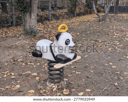 Nostalgic playground scene with a panda spring toy and yellow ginkgo leaves