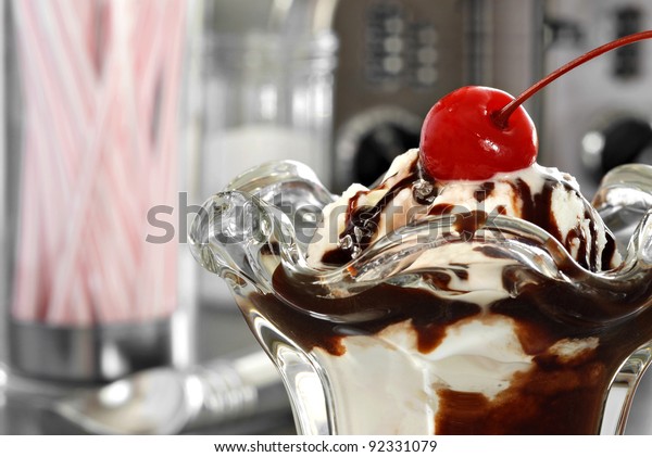 Nostalgic still life of hot fudge sundae in classic\
tulip dish with retro diner objects in background.  Macro with\
shallow dof.