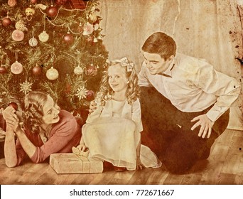 Nostalgy Christmas Family With Child Girl Dressing Christmas Tree. Xmas Tree Presents For Happy People. Home Portrait Vintage Sepia Old Retro Photo 1910-1940.