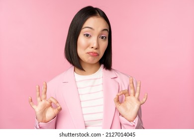 Not Bad. Impressed Businesswoman, Asian Office Lady Showing Okay Sign And Nod In Approval, Standing Over Pink Background